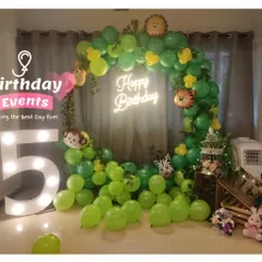 A fun jungle-themed 5th birthday. The room is filled with green balloons, animal foil balloons, and a large marquee number "5".