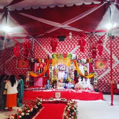 A full view of a large-scale satsang decoration inside a tent. The main stage is elaborately decorated with flowers, lighting, and portraits, creating a divine focal point for the event.