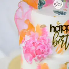 A close-up of the tropical flamingo cake, highlighting the delicate, hand-made wafer paper flower and painted leaf details.
