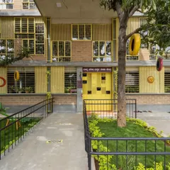The facade of the Mathru Centre for Developmental Disabilities. We used reclaimed windows from another project, painting them a bright, cheerful yellow to create a welcoming and visually stimulating entrance. The ramp ensures the building is accessible to all.