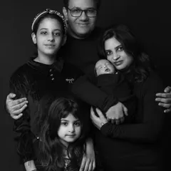 Welcoming the newest member. This classic black and white portrait captures the entire family, including proud older siblings, creating a timeless piece of art for their home.
