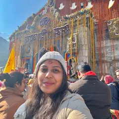 A happy traveler's selfie in front of the Kedarnath temple. Her smile and the tilak on her forehead reflect the inner peace and joy of a successful pilgrimage.