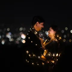 A romantic embrace wrapped in fairy lights, with the city lights creating a beautiful bokeh background. This is a simple yet stunning way to create a magical night portrait.