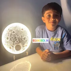 Look at that proud smile! Here is a young creator with his finished Moon Lamp, glowing brightly. He carefully crafted all the craters and textures himself to make it look just like the real moon.