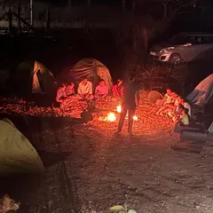 Our campsite at night, with tents pitched and trekkers gathered around a crackling campfire. This is the perfect end to a day of hiking.