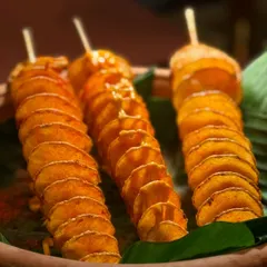 A still shot of our popular Spiral Potatoes. Served on a banana leaf, this simple dish is elevated by its presentation and delicious seasoning.