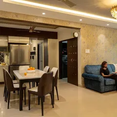 Here is a wide view of the renovated 'Blue Elegance' living and dining room. The space is unified by a soft, neutral palette, elegant floral wallpaper, and modern lighting, creating a sophisticated communal area.