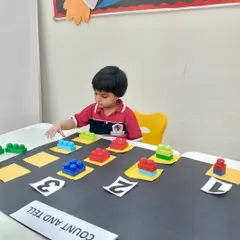 This young learner is deeply engaged in our block counting exercise. By physically handling the blocks, he develops a tangible understanding of numbers and patterns, which is a core part of our creative math enrichment.