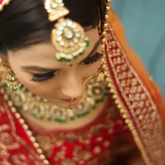 A top-down shot emphasizing the bride's intricate maang tikka and stunning eye makeup. This angle provides a unique perspective on the bridal details and makeup artistry.