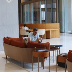 A customer working on his phone in our spacious lounge area, showcasing the different zones available for various work styles.
