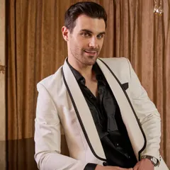 A close-up view of the white tuxedo jacket, highlighting the structure of the shawl lapel and the impeccable fit across the shoulders. Paired with a black shirt, this look is the epitome of modern elegance.