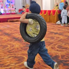 This is how we party at JuniorFit. A young guest at a fitness-themed birthday celebration carries a tire as part of a fun and challenging obstacle course, proving that birthdays can be both active and awesome.