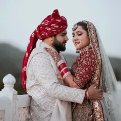 An intimate portrait of Sahil and Shikha against the backdrop of the Jaipur mountains. The groom's red turban complements the bride's beautiful lehenga, creating a picture of royal elegance.
