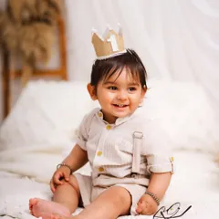 Dressed in a smart neutral outfit, this little boy's happy smile is the centerpiece of the photograph. The simple setting keeps the focus entirely on him.