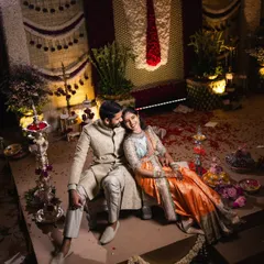An overhead shot of the couple during their Muhurtham ceremony. The traditional floral backdrop and scattered petals on the stage create a rich and celebratory setting for this important ritual.