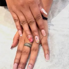 Your nails deserve to tell a story. This custom set features classic French tips alongside accent nails with pink hearts, glitter, and a tiny evil eye charm for good vibes.