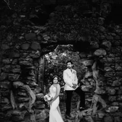 A black and white version of the couple's portrait, emphasizing the texture of the ancient stones and the contrast of their formal outfits. This is a powerful, high-fashion look.