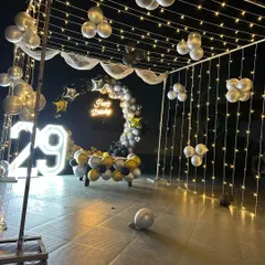 An elaborate outdoor terrace setup for a 29th anniversary or birthday party. The large neon-style marquee numbers are visible from a distance and look stunning against the fairy light canopy.
