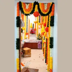 A traditional entrance decoration featuring hanging garlands of orange, yellow, and white flowers. This classic design is perfect for creating a festive and welcoming passage into a home or office.