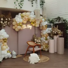 A slightly different angle of our popular boho-chic "Oh Baby" setup. This view shows the layered effect of the balloon arch, the placement of the macrame hangings, and the soft lighting that creates a warm, inviting atmosphere.