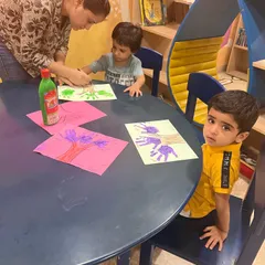 Here I am helping a child with their handprint art. These activities are not just about the final product, but about the process of creating, feeling the paint, and seeing their own hands make something new.