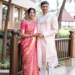 A full-length portrait of the beautifully coordinated couple. The bride's Kanjeevaram and the groom's simple, elegant drape create a timeless look.