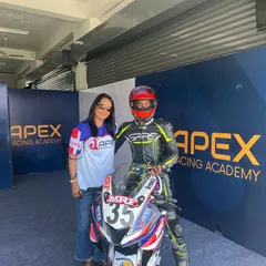 The support system is everything. A rider in full gear poses with a team member next to his race-prepped Yamaha R15 inside the Apex Racing Academy pit garage.