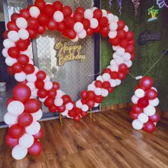A large heart-shaped balloon arch made of red and white balloons, creating a dramatic entrance or photo spot.