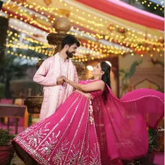 A beautiful shot of the couple during their Mehndi ceremony, with the bride twirling in her stunning pink lehenga under festive lights.
