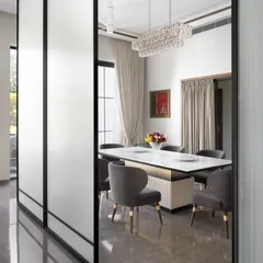 This formal dining room is defined by its elegant simplicity. A contemporary chandelier hangs over a marble-topped table, and frosted glass panels can be used to create a more intimate setting when desired.