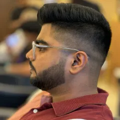 A sharp men's haircut focusing on the details. This style features a clean skin fade that blends seamlessly into a voluminous, textured top, paired with a perfectly lined-up beard.