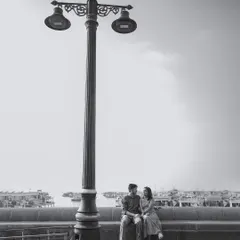 A timeless black and white portrait of Nikit and Anusha sitting by a classic Mumbai lamppost, with the city's waterfront creating a serene and classic romantic photograph.