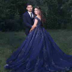 A beautiful couple portrait from an engagement shoot. Her makeup was designed to look fresh and radiant in natural outdoor lighting, featuring soft contouring and a natural lip that complements her elaborate blue gown.