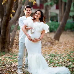 A classic pregnancy announcement photo, with the couple holding up a tiny pair of baby shoes together. A symbol of their shared excitement and future.
