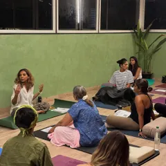 A space for listening and sharing. An instructor guides a discussion during a Yoga Nidra workshop, creating a safe environment for participants to connect before resting.
