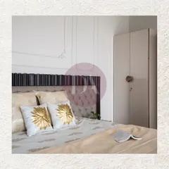 A close-up of a beautifully styled bed, featuring pillows with gold foil embroidery. The headboard combines a dark fluted wood frame with a classic tufted panel, adding texture and a touch of luxury.