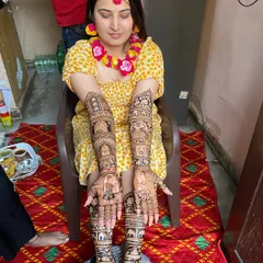 Here is a beautiful bride showing her full bridal mehandi. The design goes all the way up her arms and also covers her feet, filled with traditional figures and patterns for a complete wedding look.