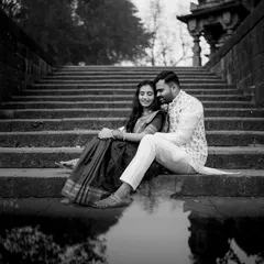 A serene and artistic pre-wedding portrait. The reflection in the water and the historic setting are enhanced by the dramatic contrast of black and white.