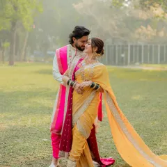 A classic, romantic pose set against the soft light of a park. We composed this shot to feature the full length of the bride's stunning yellow nauvari saree and the couple's loving gaze.