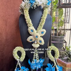 A beautiful floral jewellery set for a baby girl's special day. This set, made with Tagar buds and blue orchids, includes a tiara, necklace, and matching handcuffs.