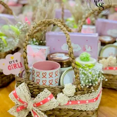 A charming "It's a Girl!" baby announcement hamper. This rustic basket is filled with sweet treats, a cute mug, and delicate flowers, all tied together with lace and polka dot ribbon for a touch of vintage charm.