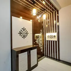 This entryway design features a glossy, dark wood shoe cabinet and a decorative wall partition. The intricate details and integrated lighting create a luxurious and welcoming first impression for the home.