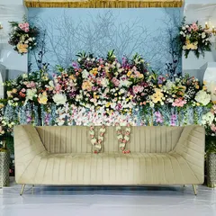 This royal reception stage combines intricate floral arrangements with elegant chandeliers and a soft blue backdrop. The design exudes a sense of timeless luxury and sophistication.