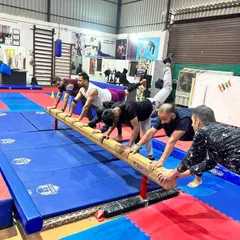 A group of adult men works on a strength conditioning drill using the balance beam. We use gymnastics equipment in creative ways for effective fitness training.