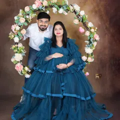 This portrait captures a beautiful moment of connection between the couple. The elegant blue gown and floral hoop create a dreamy, fairytale-like setting for this maternity shoot.
