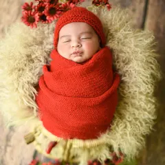 A bold and beautiful choice. The vibrant red knit wrap and matching hat make this newborn portrait stand out, surrounded by delicate red flowers.