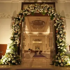 Make a grand entrance to your wedding. This magnificent floral arch, made of white flowers and lush greenery, creates a stunning entryway for the couple and their guests.