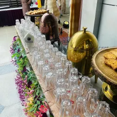 Another view of the tea station, showcasing the neat arrangement of glasses, traditional copper and brass urns, and fresh cookies. It's a welcome corner at any time during an event.