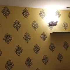 A full wall covered in a traditional damask stencil pattern, giving this room a classic, wallpaper-like appearance with a warm yellow background.