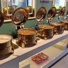 Here you can see a variety of dishes in the buffet line, including rice, a paneer curry, and dal. I make sure there's a balanced and tasty selection every day.